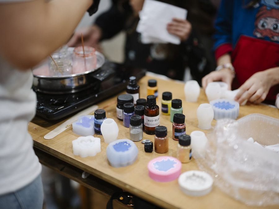 Hands making colourful craft items at a workshop table